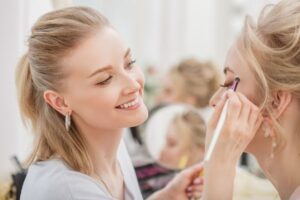 makeup artist applying wedding day makeup to bride